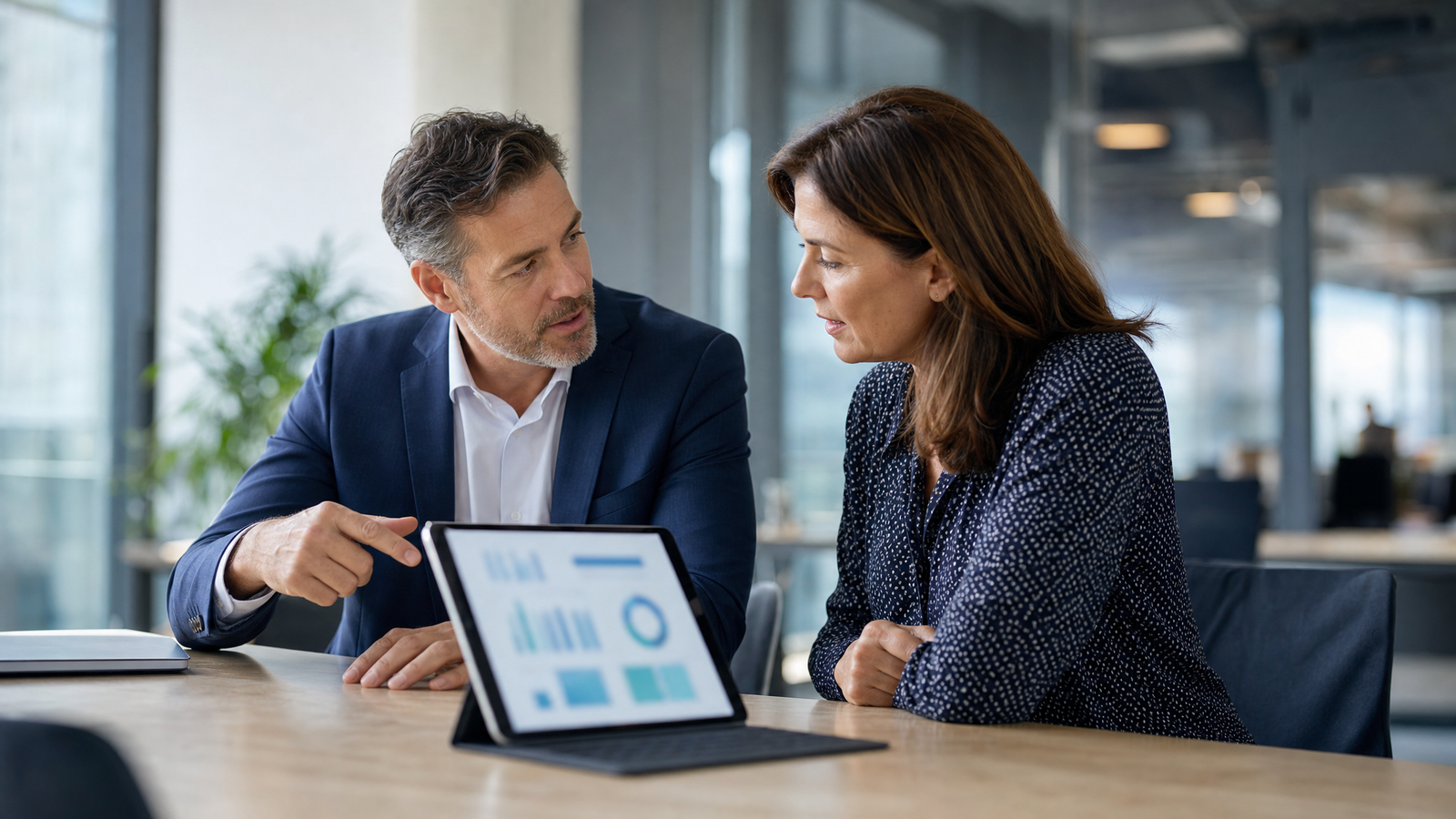 Two financial services professionals reviewing portfolio analytics on a tablet, discussing how to segment past-due customers by capacity and readiness